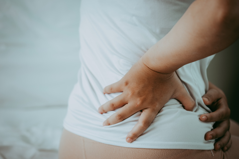 Closeup of Young Woman Suffering from Pain in Back While Sitting